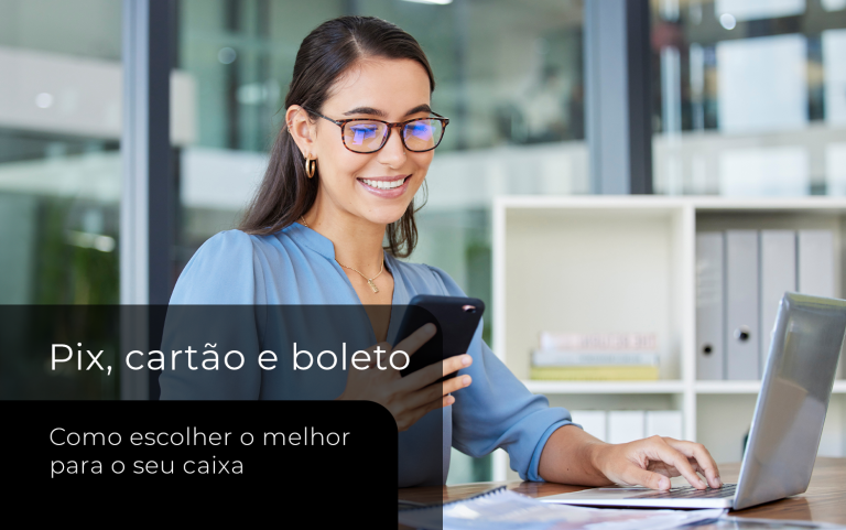 Mulher em ambiente corporativo utiliza celular e notebook enquanto consulta informações sobre formas de pagamento para empresas.