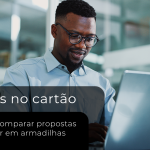 Homem analisando propostas de taxas de cartão para lojista em um notebook, em ambiente corporativo.