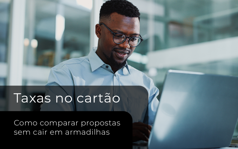 Homem analisando propostas de taxas de cartão para lojista em um notebook, em ambiente corporativo.